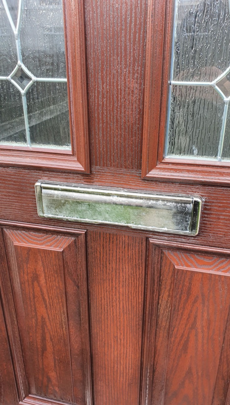 image shows the centre section of a colour restored composite door with gold letterbox