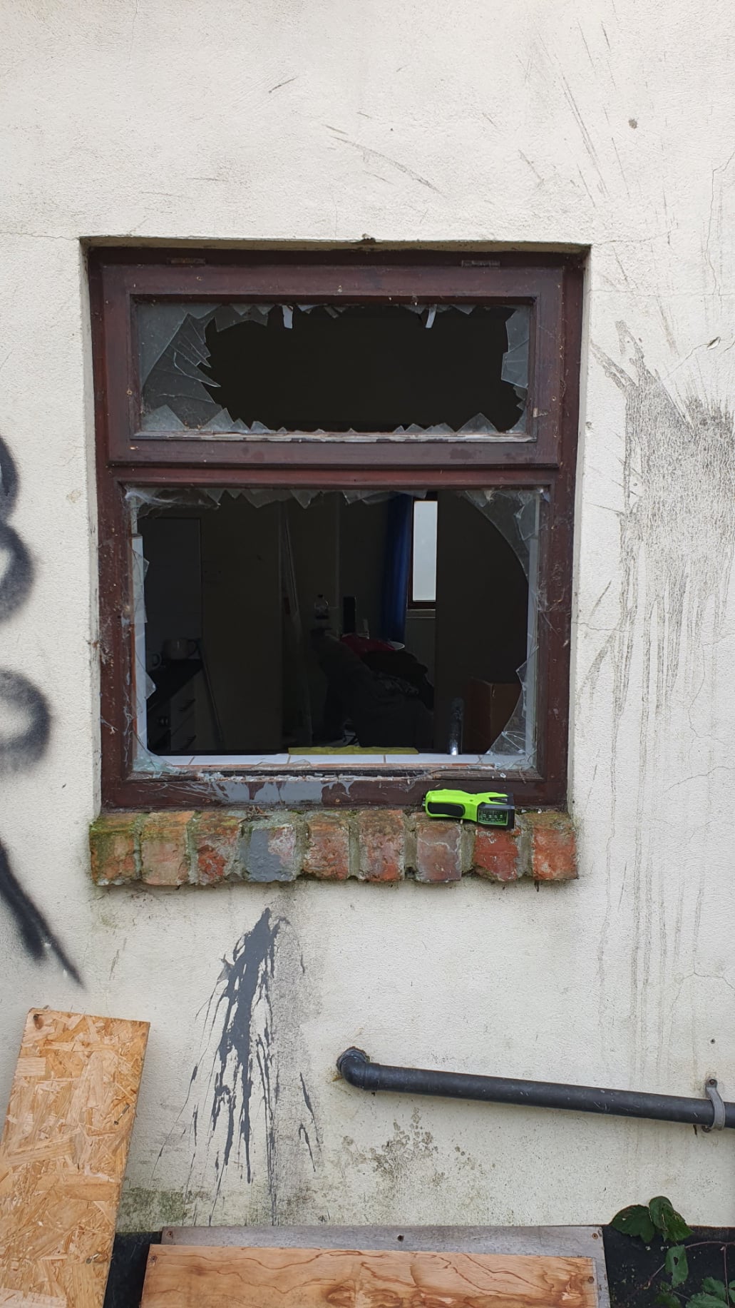 “Broken double‑glazed window with a large hole and shattered glass, with a Double Glazing Repairs service van visible outside.